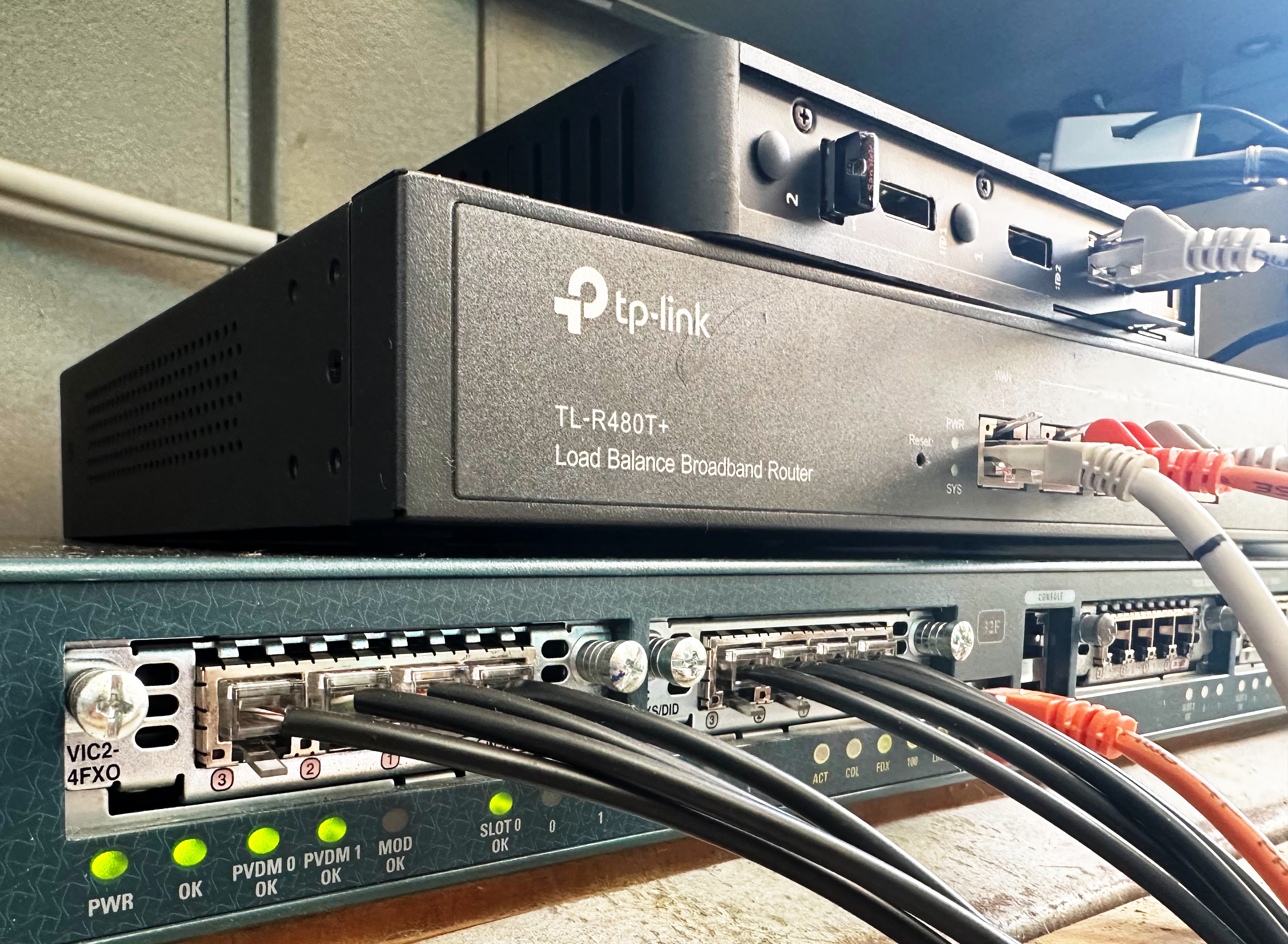 photo of a small stack of networking equipment, with a cisco 1760, a TP-Link TL-R480T and a Dell thin client